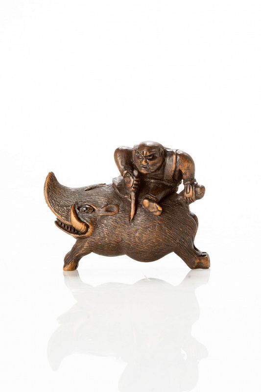 A boxwood netsuke of Nitta No Shiro riding a boar