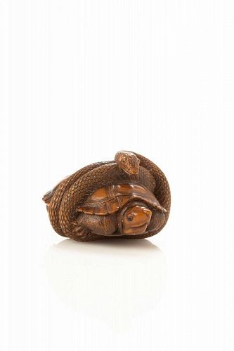 A Japanese boxwood netsuke depicting a snake with a turtle