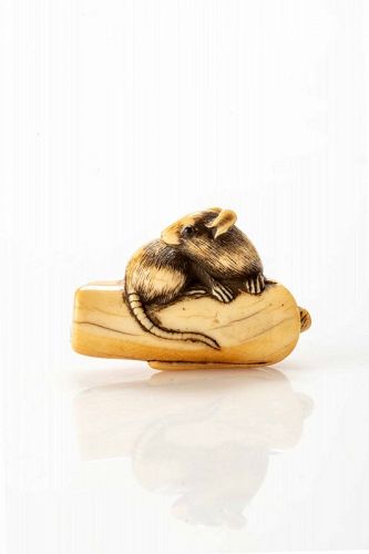 An ivory netsuke depicting a mouse crouching on an overturned candle