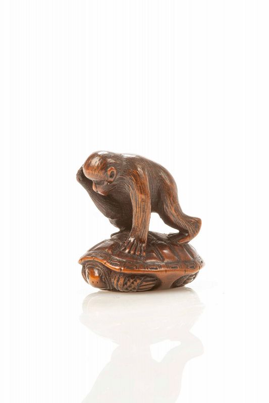 A boxwood netsuke depicting a monkey trying to catch a turtle