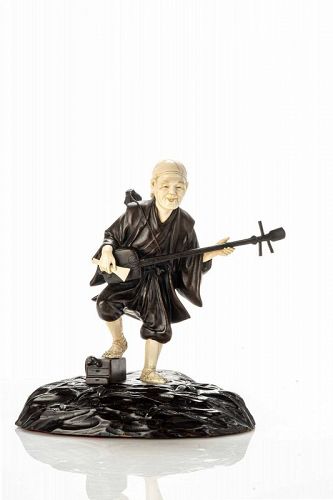 A bronze and ivory okimono depicting a street entertainer