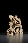 An exceptional ivory okimono depicting a snake wrapping around a cliff