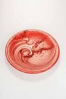 A lacquered wooden plate decorated in relief with a majestic wave