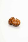 A Japanese corozo nut netsuke depicting two chestnuts, signed Ikko