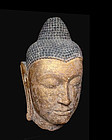 A large Thai stone gilt Buddha head, Ayutthaya 16th C