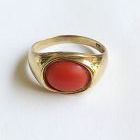 A NATURAL ORANGE CABOCHON CORAL RING SET IN YELLOW GOLD.