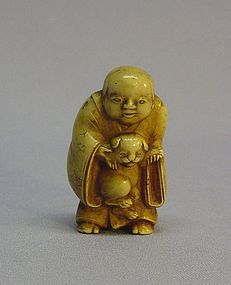 JAPANESE CARVED NETSUKE OF A CHILD HOLDING A PUPPY