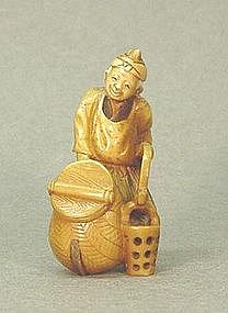 JAPANESE CARVED IVORY NETSUKE OF A MAN HOLDING BUCKET