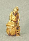 JAPANESE CARVED IVORY NETSUKE OF A MAN HOLDING BUCKET