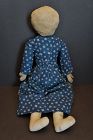 A pencil face doll with big eyes wearing a blue calico dress