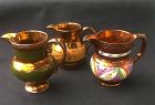 Three Staffordshire copper lustre jugs: green, orange and Gaudy