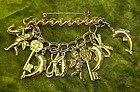 Gold tone links bar pin, angels, dolphins, key charms
