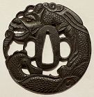 A strongly carved iron sukashi Kinai tsuba depicting a coiled dragon