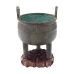 A Chinese Archaistic Bronze Tripod Censer on a Carved Wood Base.